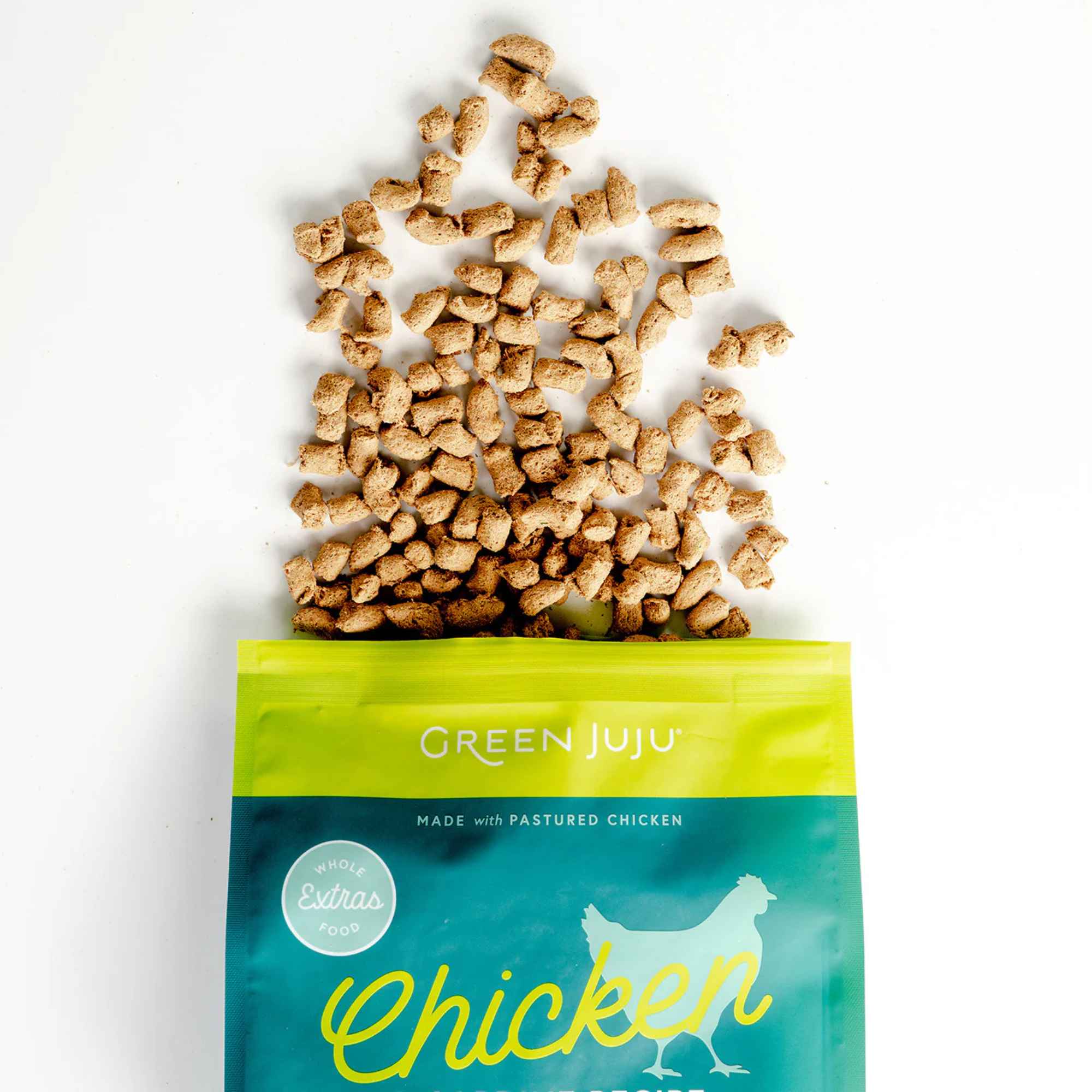 Green Juju chicken &amp; sardine freeze dried raw recipe packaging with scattered food on a white background