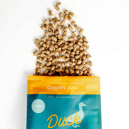 Green Juju Duck &amp; Sardine pet food packaging with spilled freeze dried raw nibbles on a white background